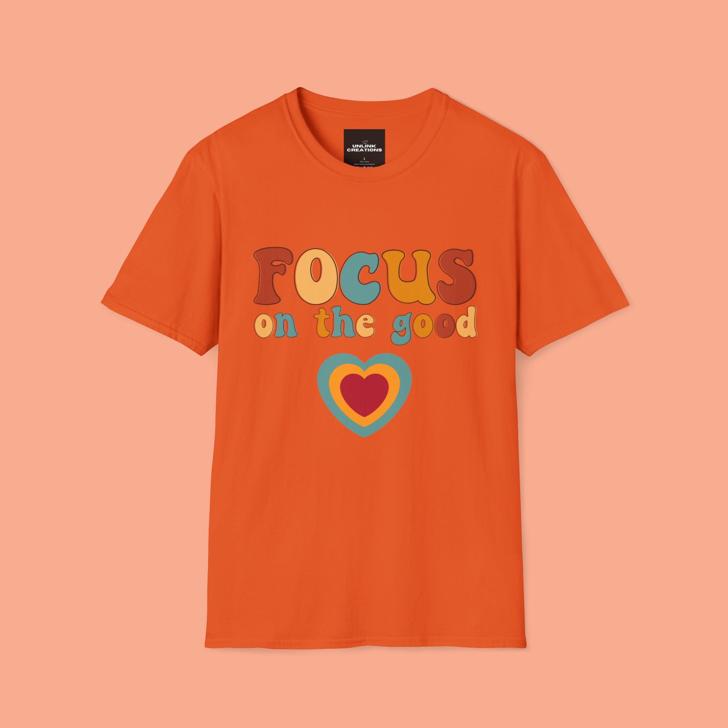 “FOCUS on the good” above a multicolored heart on this Unisex Softstyle T-Shirt.