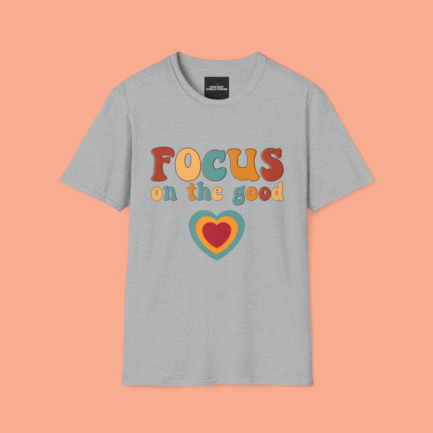 “FOCUS on the good” above a multicolored heart on this Unisex Softstyle T-Shirt.