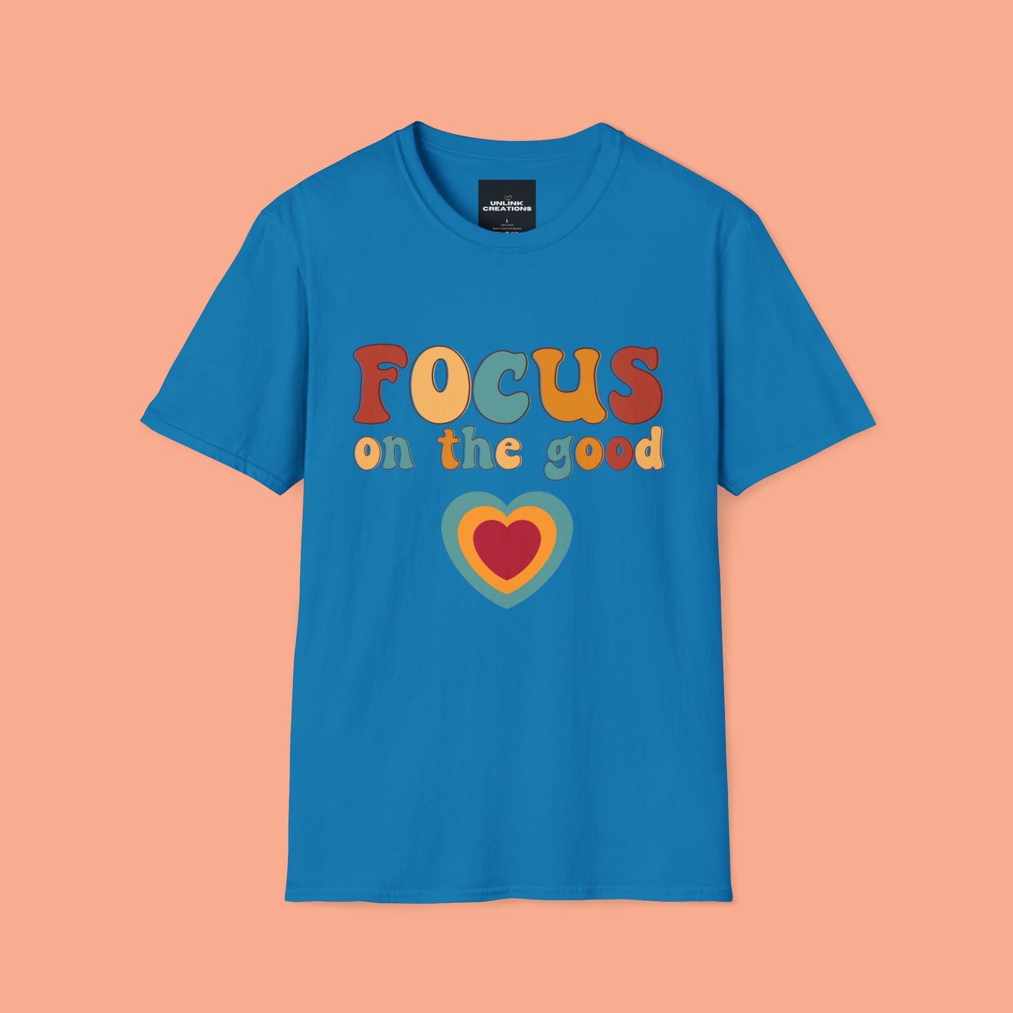 “FOCUS on the good” above a multicolored heart on this Unisex Softstyle T-Shirt.
