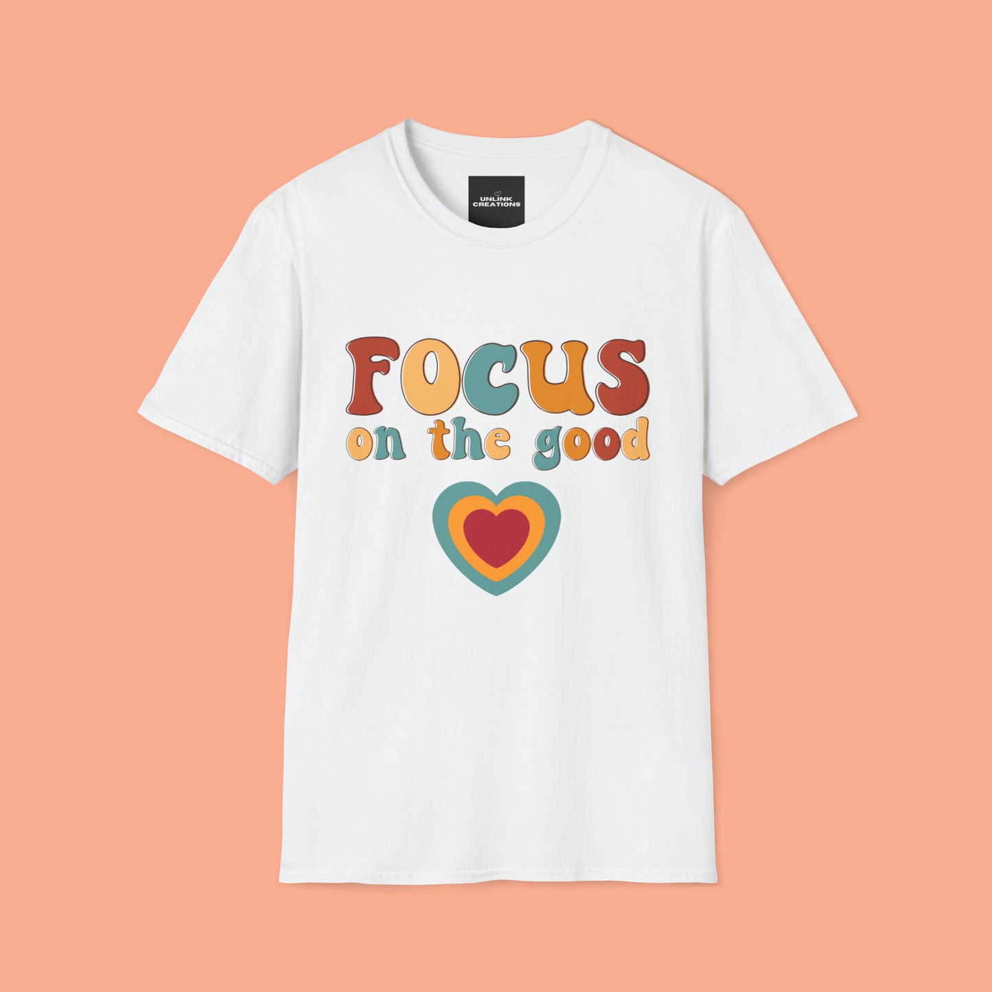 “FOCUS on the good” above a multicolored heart on this Unisex Softstyle T-Shirt.
